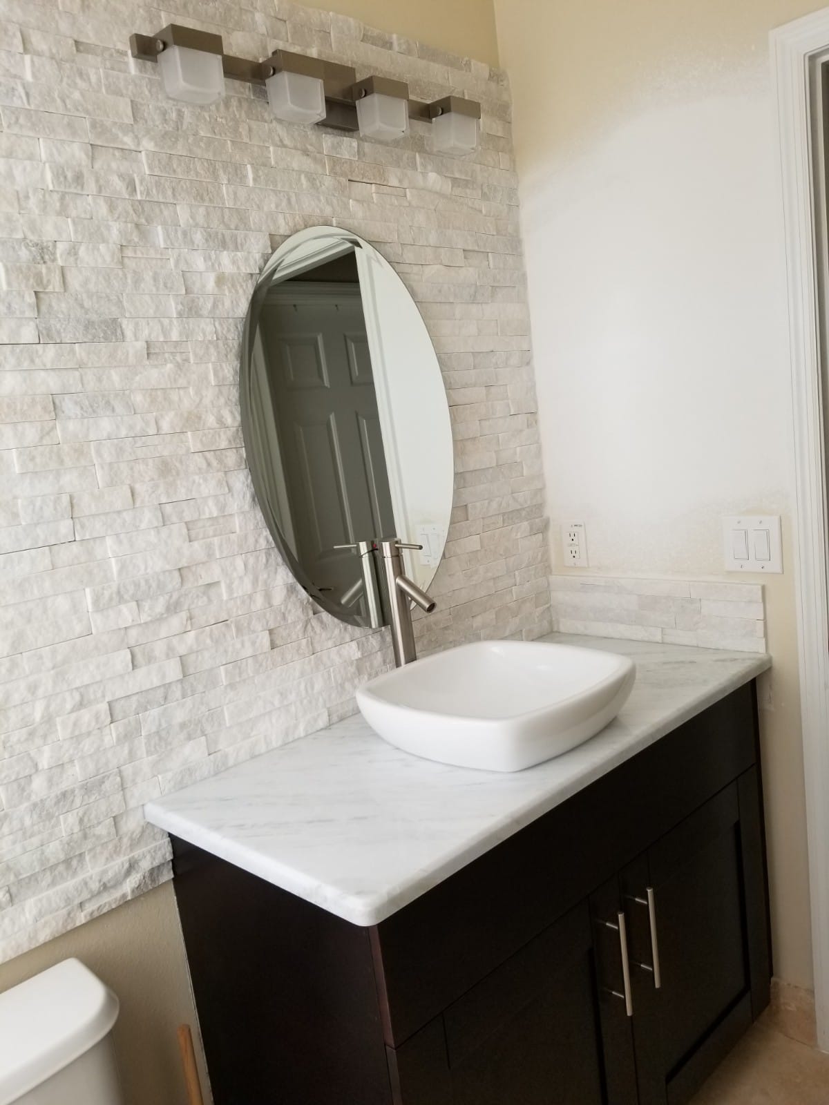 Modern bathroom sink with an oval mirror and a textured white wall