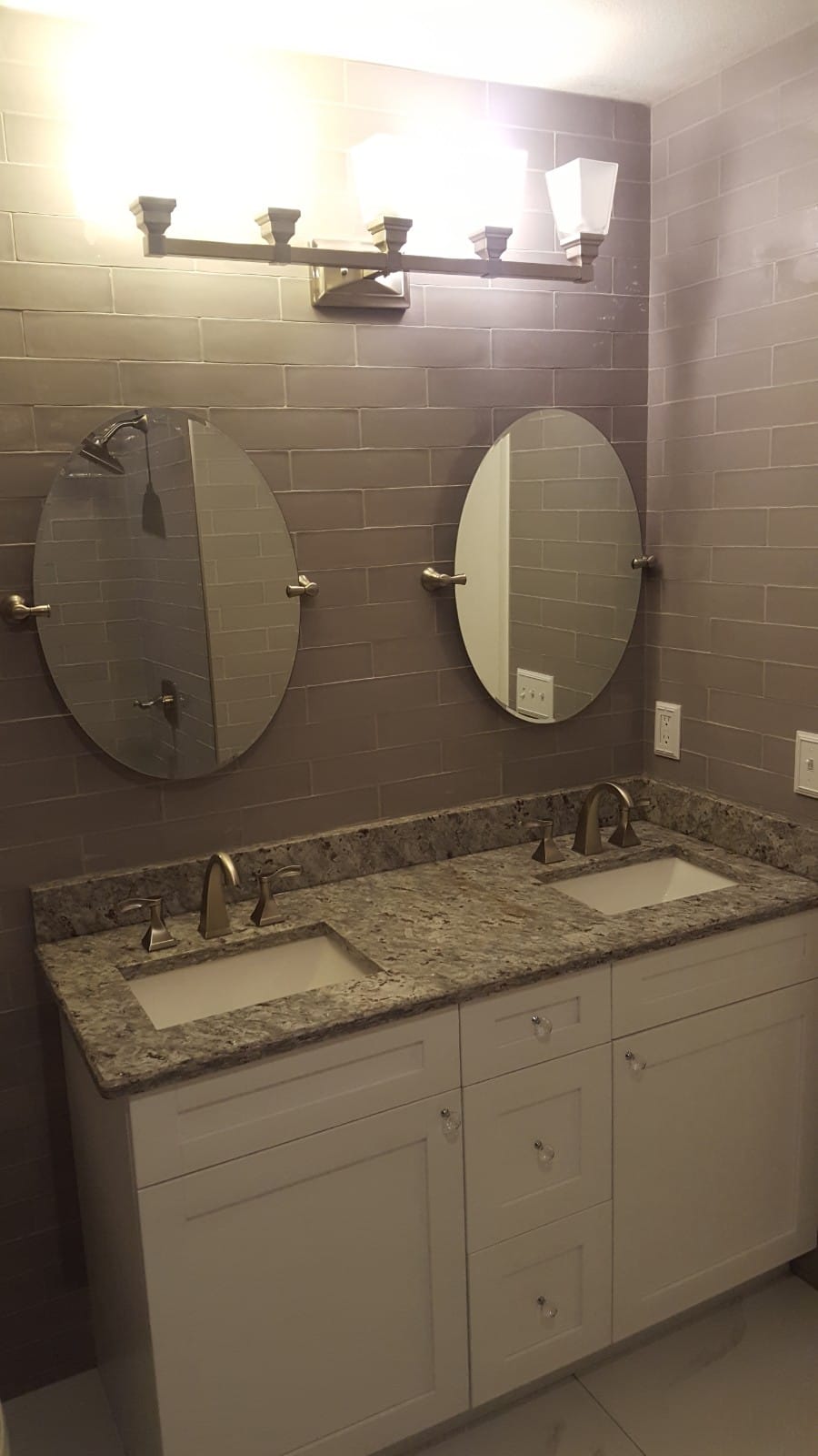 Modern double sink bathroom vanity with oval mirrors and a granite countertop