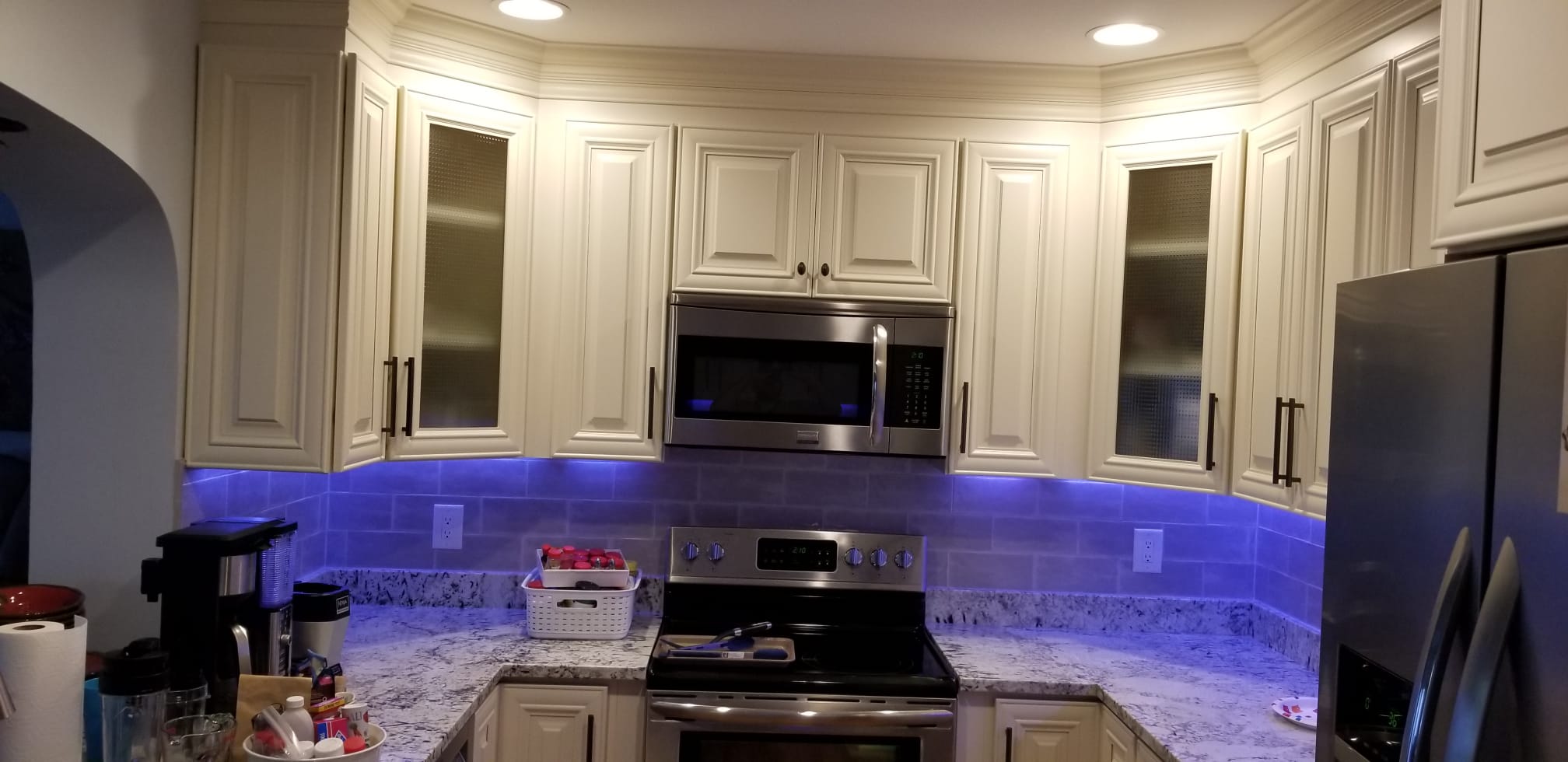 Modern kitchen with white cabinets and blue under-cabinet lighting