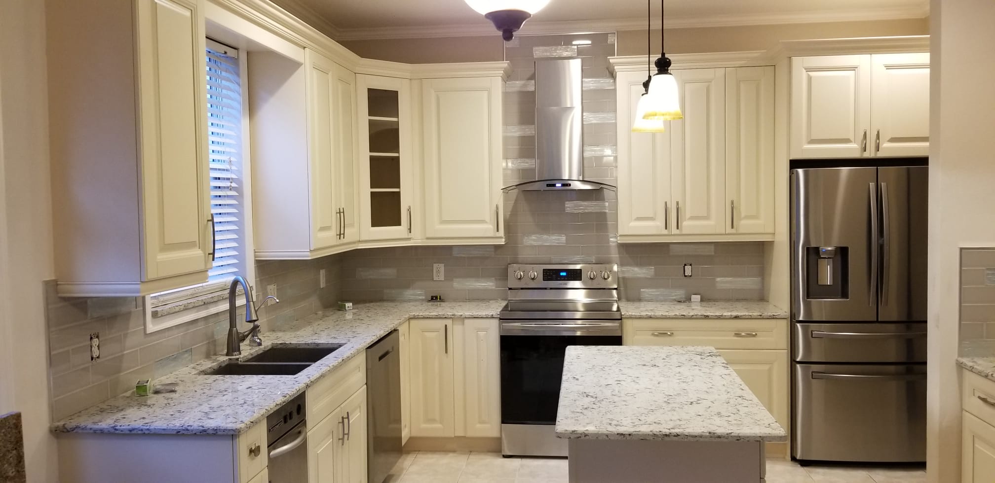 Brightly lit kitchen with new appliances and fitted cabinetry