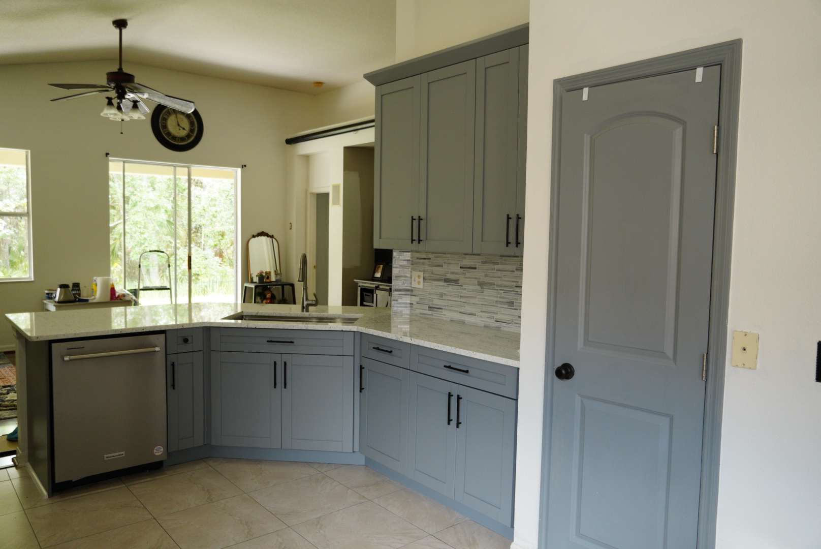 Grey shaker cabinetry and a painted pantry door in the finished kitchen