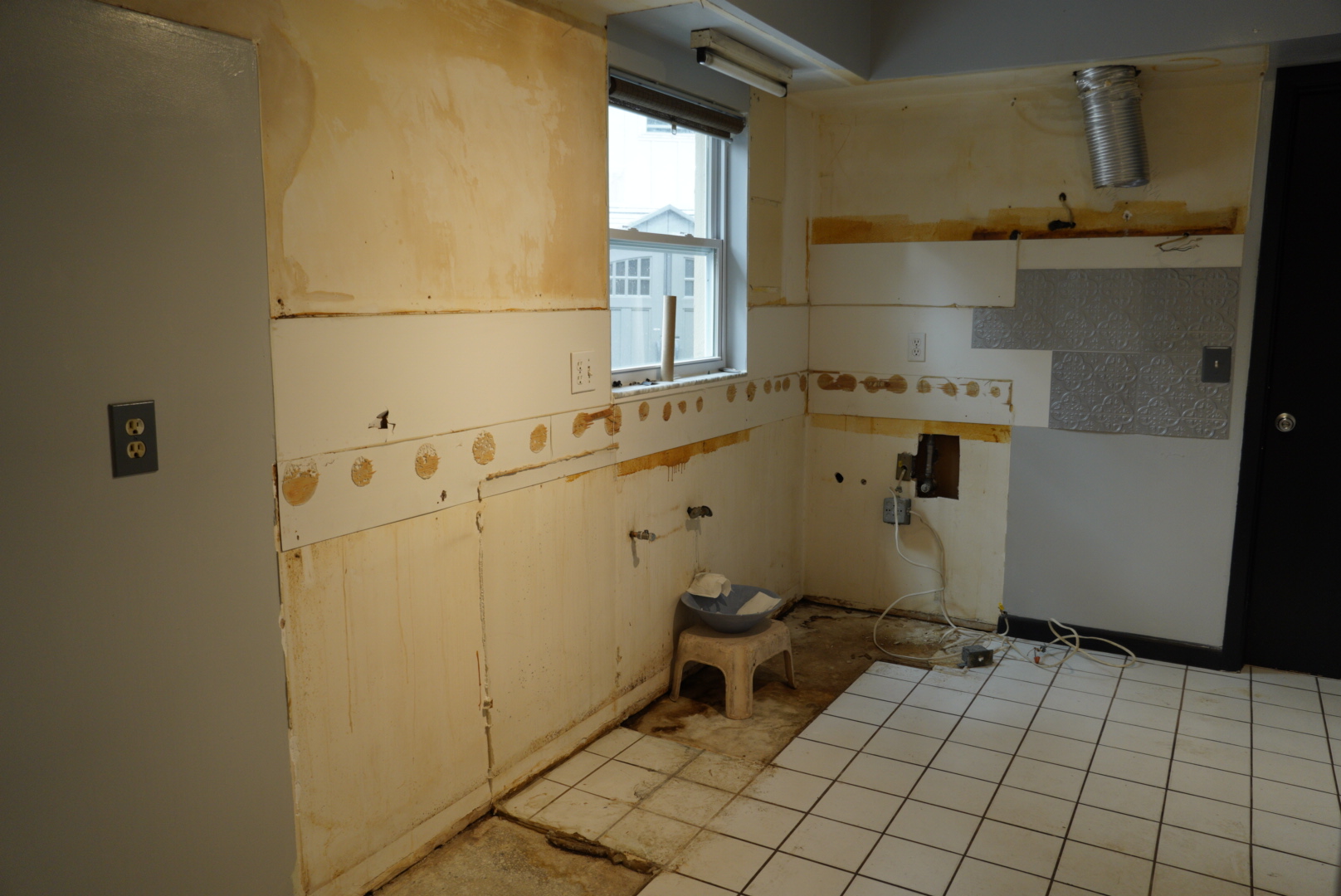 The same kitchen mid-demolition, with cabinets removed and walls stripped back