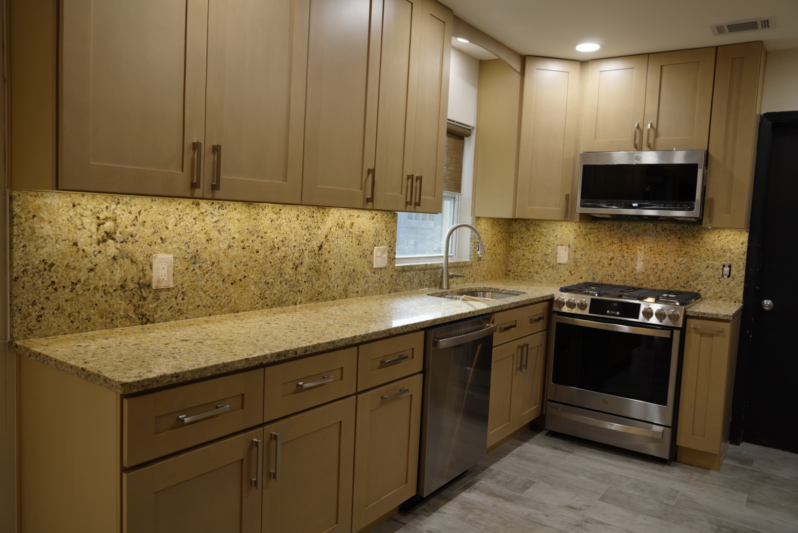 Maple shaker kitchen with granite countertops, a full granite backsplash and stainless appliances