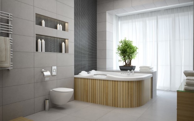A grey tiled bathroom with a mosaic feature wall, recessed niches and a panelled corner tub