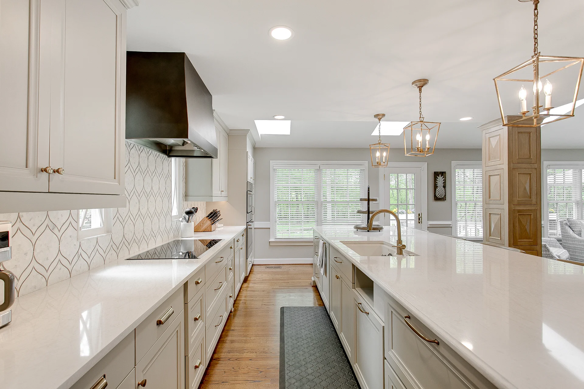 Modern white kitchen remodel with quartz countertops and gold lantern pendants